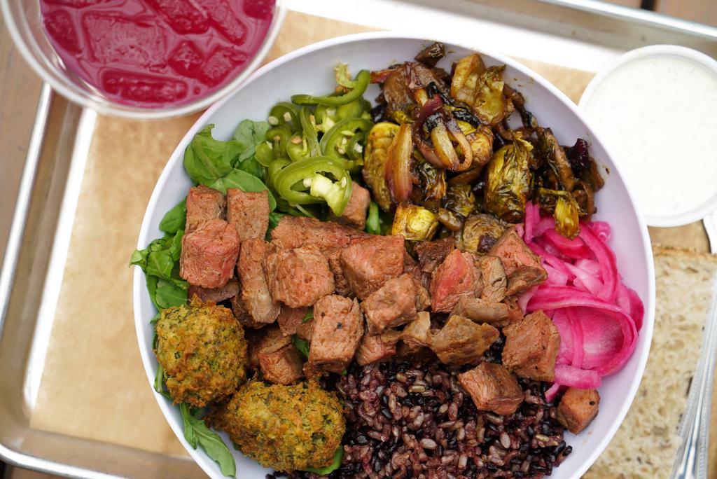 Tri Tip Steak Warm Rice Bowl · Purple rice, grass-fed steak, roasted vegetables, falafel, arugula, pickled jalapenos, pickled red onions, and beef bone broth. Suggested with ranch dressing. Includes roasted sweet potatoes.