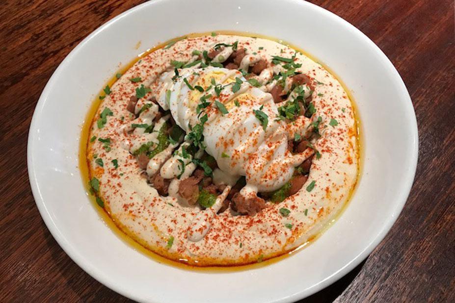Fava Hummus · Egyptian fava beans, hard boiled egg and green sauce. Topped with parsley, paprika, and extra virgin olive oil. Gluten-free.