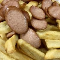 Salchipapas · Sliced hot dogs on top of french fries served with sauce on the side.