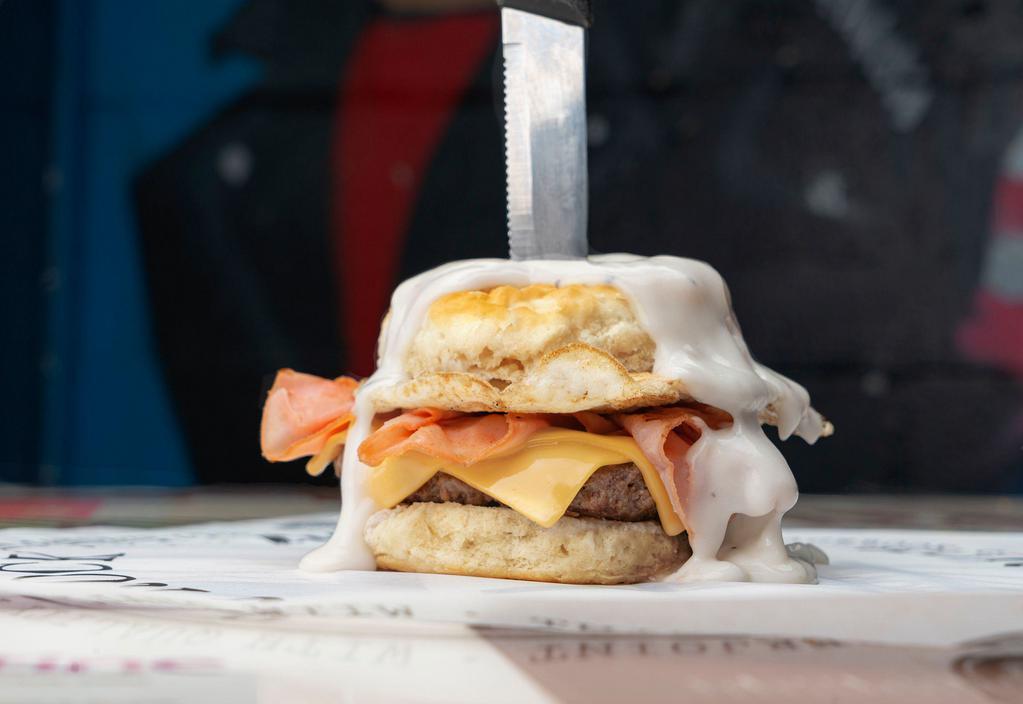 The Freddy D · A ¼ bacon beef blend patty, grilled ham, melted American cheese, fried egg on biscuit buns and smothered in white gravy.