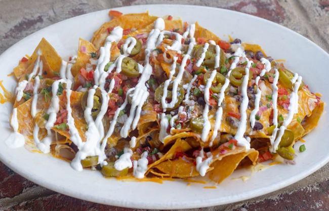 Ultimate Nachos · tortilla chips, pico de gallo, sour cream, jalapenos, fresh salsa, queso, cilantro, black beans, melted jack and cheddar cheese Add Chicken $2 Add chili $2 Add Guac $2 Add Beyond Meat $4