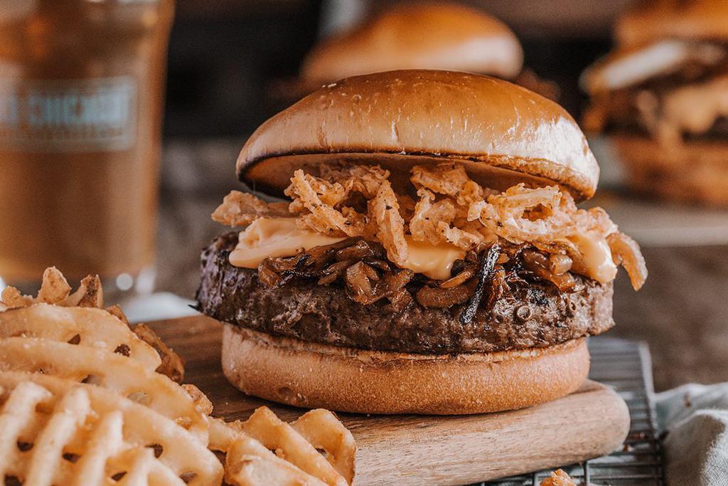 CRAFTED BEER BURGER · USDA Choice ground chuck burger grilled with a light lager & smothered in caramelized onions & beer cheese sauce made with Guinness, crispy onion strings.