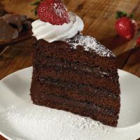 DARK CHOCOLATE FUDGE CAKE · Four layers of chocolate cake & rich fudge frosting, whipped cream, powdered sugar & a straw...