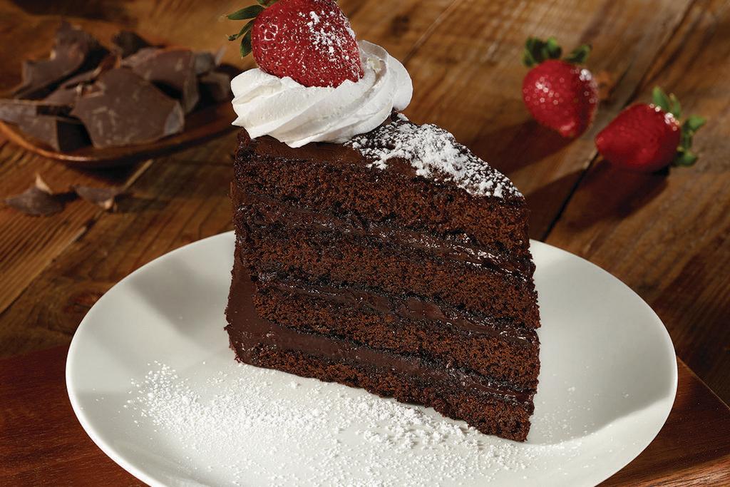 DARK CHOCOLATE FUDGE CAKE · Four layers of chocolate cake & rich fudge frosting, whipped cream, powdered sugar & a strawberry.