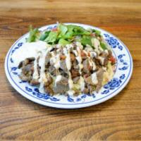 19. Beef Shawarma · Slices of beef shawarma grilled with tomatoes served with tahini sauce, rice pilaf, salad, a...