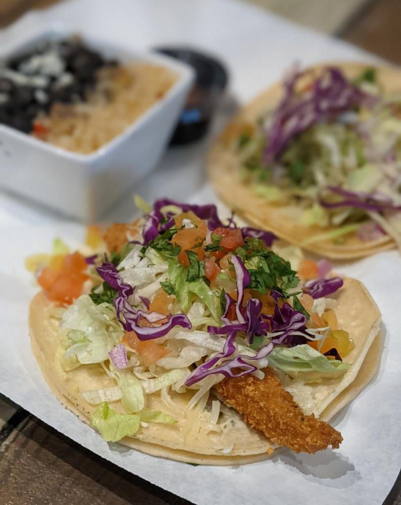 Double Taco Meal · Two Signature Tacos - Built on Steamed White Corn Tortillas; with: Chihuahua Cheese, Lettuce, Tomato, Red Onion, Purple Cabbage, Queso Fresco & Roasted Garlic Aioli Sauce.  Served with Chips and Salsa and a Side of Your Choice.