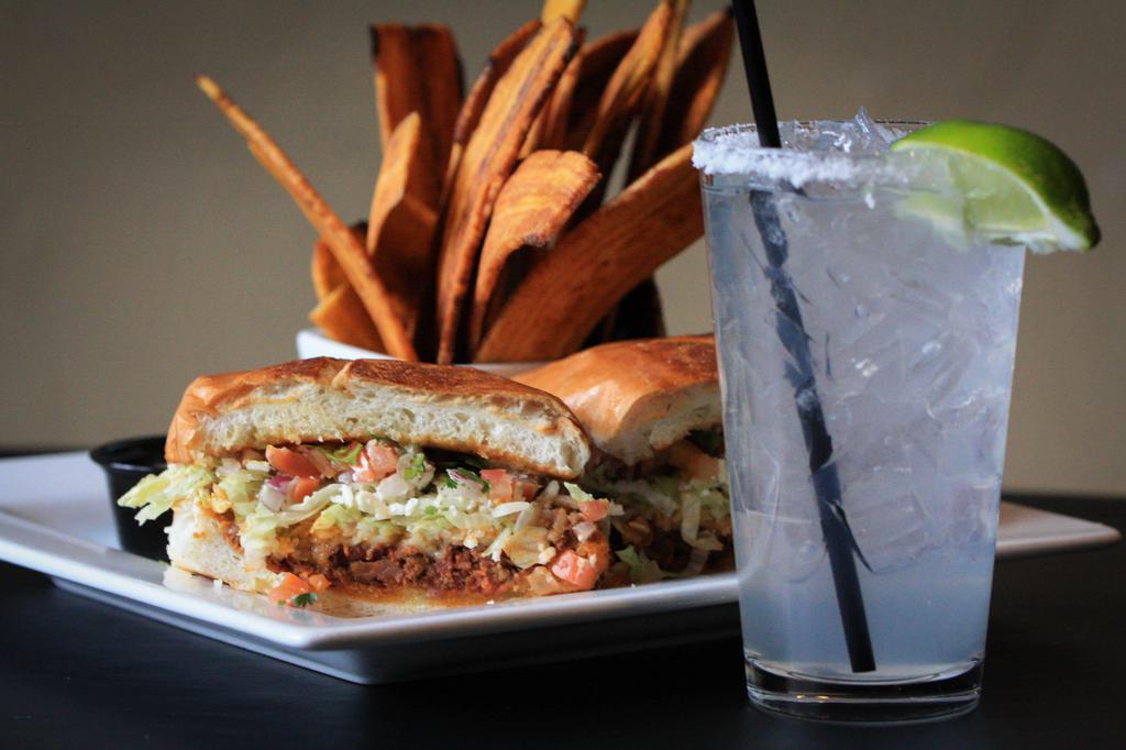 Garlic Shredded Beef Sandwich · Served with fried plantains, made on grilled torta bread with roasted garlic aioli sauce, chihuahua cheese, queso fresco, cilantro, lettuce, tomato and red onion.