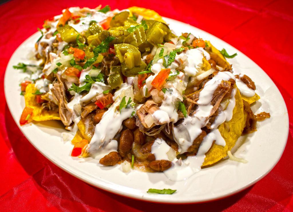 Nachos · Our Nachos consists of: House made corn tortilla chips, piled with your choice of meat, pot beans, mozzarella cheese, pico de gallo, pickled jalapenos, drizzled with sour cream and chipotle sauce.