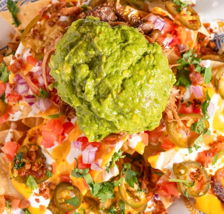 Loaded Nachos · Choice of Beer-braised pulled pork, Grilled Chicken, or Plant-based protein, nacho cheese, tomato, red onion, Jalapeno, sour cream, cilantro, bacon bits, guacamole and corn tortilla chips.