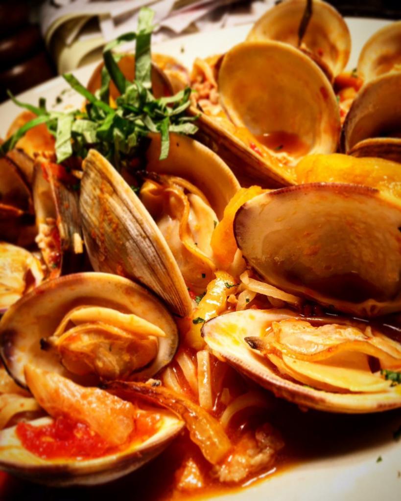 Clam Zuppa · Native littlenecks, Italian sausage, onions, garlic, fresh basil, spicy-tomato clam broth, crostini.