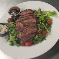 Montreal Flat Iron Steak Salad · 6 oz. Angus Reserve, tomato, red onion, blue cheese, and balsamic dressing.