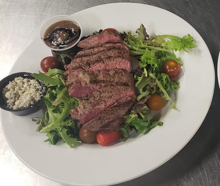 Montreal Flat Iron Steak Salad · 6 oz. Angus Reserve, tomato, red onion, blue cheese, and balsamic dressing.