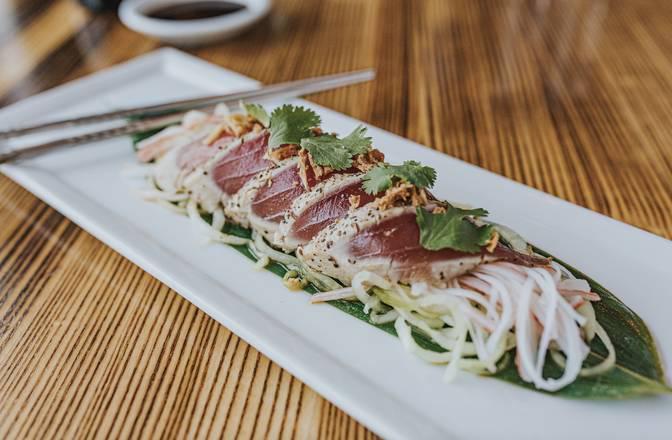 Tuna Tataki · Seared tuna sashimi over a bed of cucumber with krab stick, crispy onions, and citrus soy-sesame dressing. Raw.