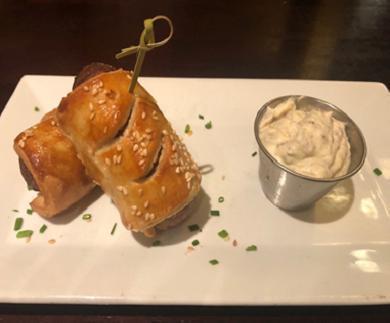 Bangers In A Blanket · Irish sausage rolled in puff pastry topped with chives and sesame seeds. Served with creamy house mustard.