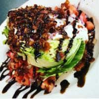 BACON BLEU WEDGE SALAD · Crisp and Hearty Iceberg Wedge Topped with Ripe Tomatoes, Crispy Bacon, Red Onions, Our Sign...