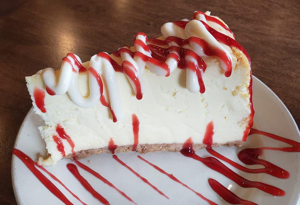 Highrise Cheesecake · Rich cheesecake with graham cracker crust topped with Vanilla Cream and Raspberry Sauce