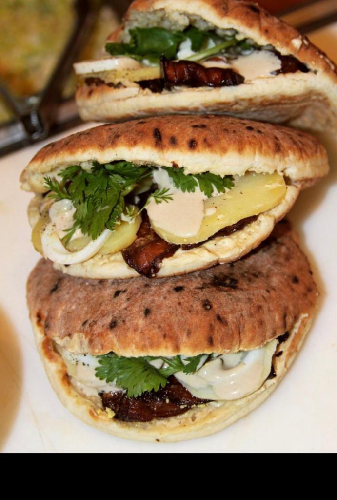 Sabich Pita Sandwich · Homemade hummus, fried eggplant, hard boiled egg, potato, Israeli salad, and fresh parsley, drizzled with tahini sauce.
