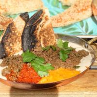 Sinya · Tahini cream topped with cooked ground beef. Pita on the side.