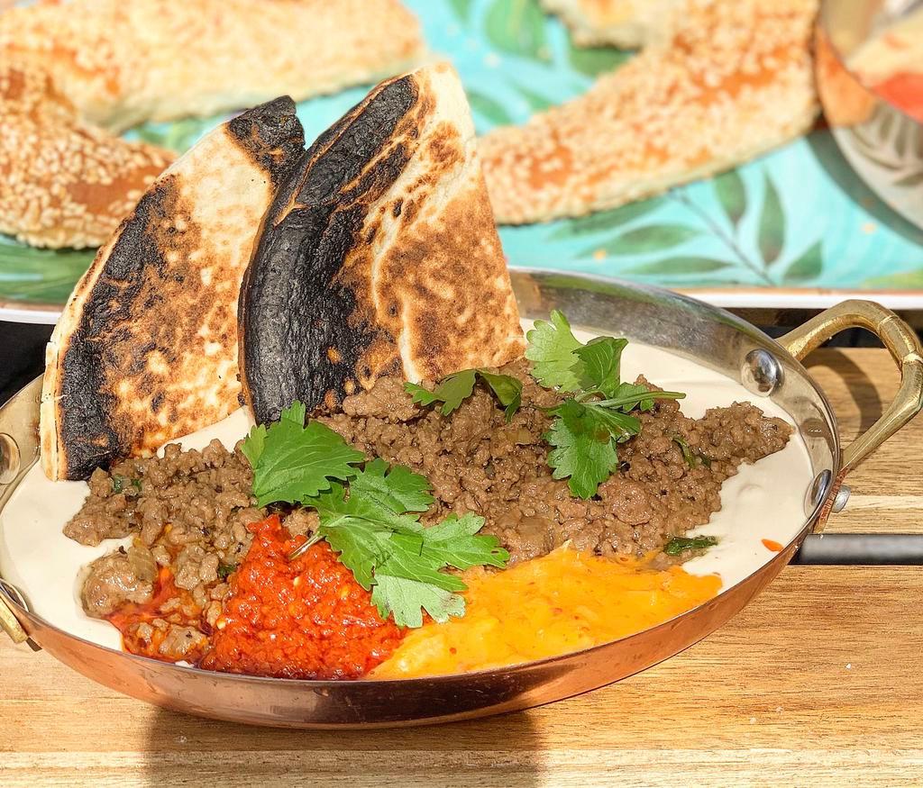 Sinya · Tahini cream topped with cooked ground beef. Pita on the side.