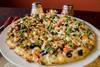 Creamy Garlic Chicken Pizza · Rich and creamy garlic sauce and mozzarella cheese with chicken breast, mushrooms, black olives, green onions, broccoli and cooked tomatoes.