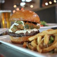 San Luis Peak Burger · Green chili cream cheese, beer battered fried poblano peppers and cilantro lime crema on a b...