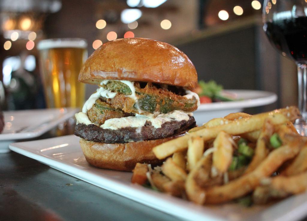 San Luis Peak Burger · Green chili cream cheese, beer battered fried poblano peppers and cilantro lime crema on a brioche bun.