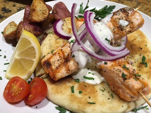 Salmon Souvlakis Dinner · Grilled sushi-grade medallions of fresh salmon fillet. Served with handmade pita, herb roasted potatoes, Greek basil, Ziziki sauce and sweet red onions.