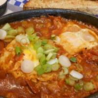 Shakshuka  · Slow cook of tomatoes, jalapenos, garlic, feta served with 2 eggs sunny side up, parsley and...
