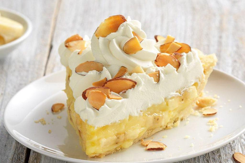 Banana Cream Pie Slice · A delicious vanilla cream filling layered with fresh, ripe banana slices inside our award-winning pastry crust. Topped with real whipped cream and toasted almonds.