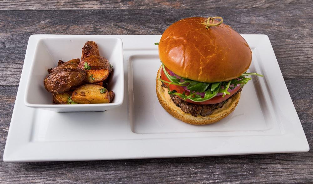 Kafta Beef Burger · Hand-formed beef, pomegranate molasses patty, mixed with minced parsley, jalapenos, onions, baby arugula, hothouse tomato, sliced red onion, sumac, chipotle hummus, bun.