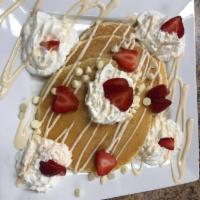 White chocolate Pancakes · White chocolate chips pancakes topped with fresh strawberries, white chocolate sauce, and wh...