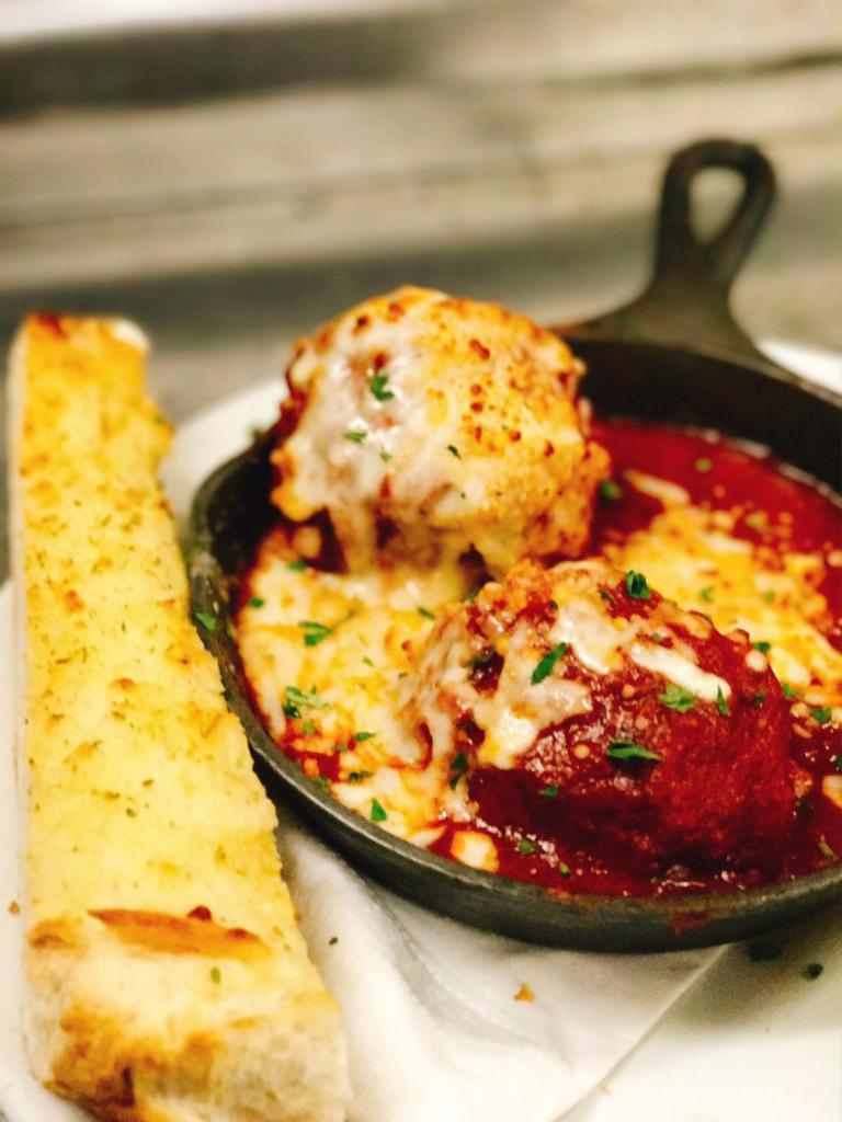 The Balls · Two of our homemade meatballs soaked in marinara and topped with Parmesan, Mozzarella and Romano. Served with garlic bread.