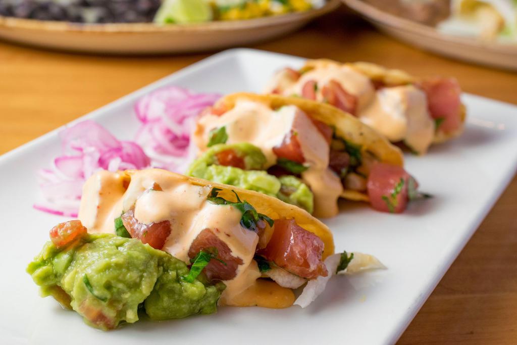 Ahi Tuna Tacos · Three crisp sushi grade tuna tacos, jicama, ginger slaw, guacamole, pickled red onion, and chipotle aioli.