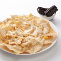 Kid's Cheese Nachos · Pile of fresh tortilla chips topped with shredded cheese and queso and served with a snack.