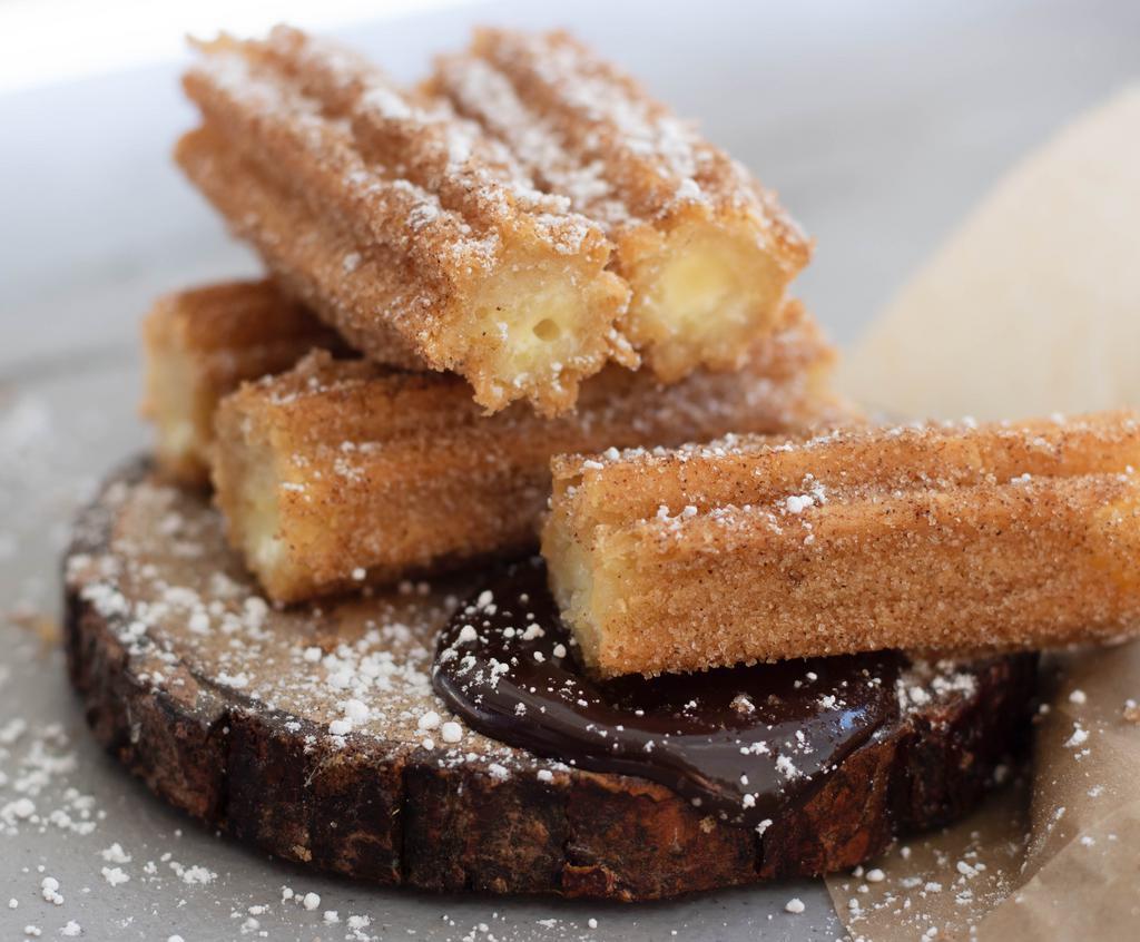 Churros · Deliciously crispy churros covered in cinnamon sugar. Comes with a side of our Chocolate Sauce ;)