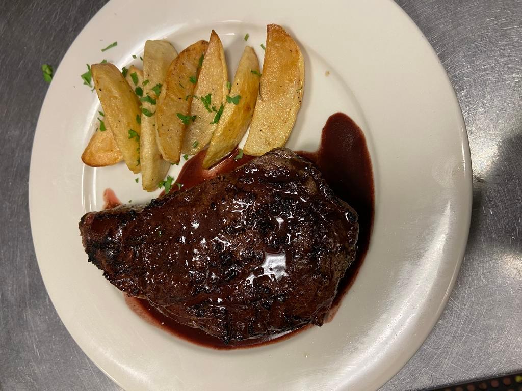 Costata di Manzo · Ribeye steak charcoal grilled and topped with port wine sauce, garnished with roasted potatoes.