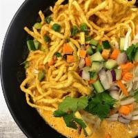 Khao Soi Gai · Yellow noodles With sliced chicken in a yellow curry sauce topped with crispy noodles, red o...