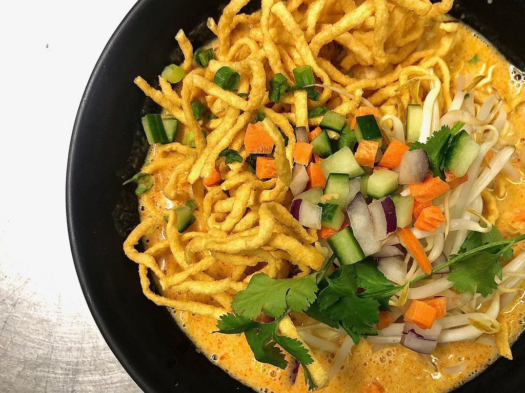 Khao Soi Gai · Yellow noodles With sliced chicken in a yellow curry sauce topped with crispy noodles, red onion, bean sprout and scallions, topped with fried onions. Spicy.