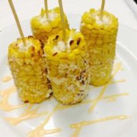 Maiz a La Parrilla · Skewered, roasted corn on the cob, sprinkled with cotija cheese, and chipotle mayo.