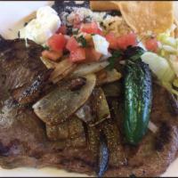 GRILLED CARNE ASADA PLATE · Grilled steak ONIONS . served with pinto  beans, rice, lettuce, pico de gallo, cheese, sour ...