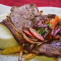 Bistec Encebollado · Grilled steak sauteed with onions, tomatoes, soy sauce, and Peruvian spices, served with ste...