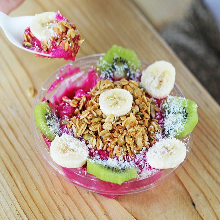 Tropical Love Bowl · Pitaya, mango, pineapple, local date puree and coconut milk. Topped with our house-made gluten-free granola, bananas, kiwi and coconut flakes.