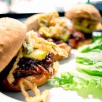 Brisket Sliders · Three sliders topped with BBQ brisket, a pickle slice and fried jalapeño onion strings.