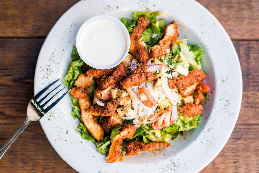 Buffalo Chicken Salad · Leafy greens topped with buffalo chicken strips, red onions, tomatoes, and bleu cheese crumbles. Bleu cheese dressing on the side.