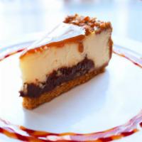 Turtle Cheesecake · Caramel sauce and chopped pecans sit atop layers of cheesecake and dark fudge, all on a Grah...
