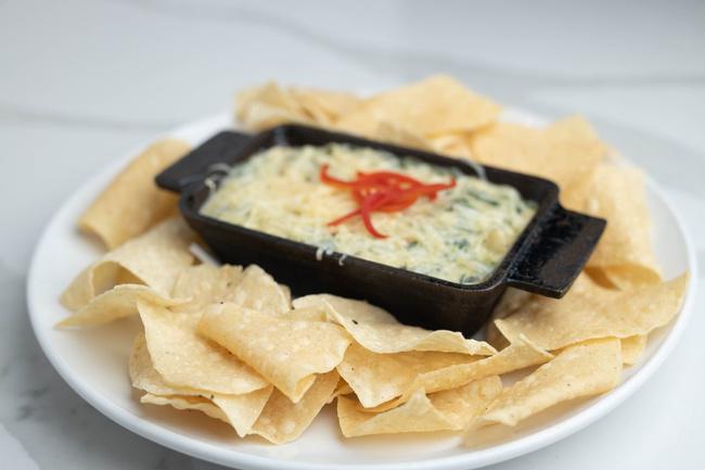 Artichoke Spinach Dip · Parmesan cream sauce prepared with spinach, artichokes, jalapeño, roasted red pepper, cayenne pepper and fresh garlic. Topped with melted White Cheddar and Parmesan cheese. Served with white corn tortilla chips.