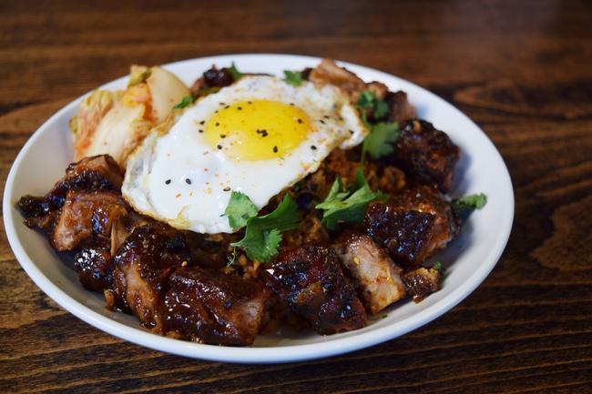 Gochuchang Korean BBQ Pork & Kimchi Fried Rice · Boneless smoked country pork ribs basted with Korean BBQ sauce and served around chopped Kimchi Fried Rice with green onions. Topped with an egg sunny side up egg.
