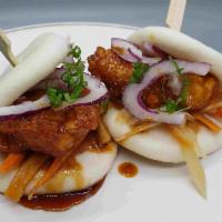 Hot Chicken Bao · Steamed bao bun stuffed with spicy soy glaze chicken, Asian slaw, red onion, and scallion.