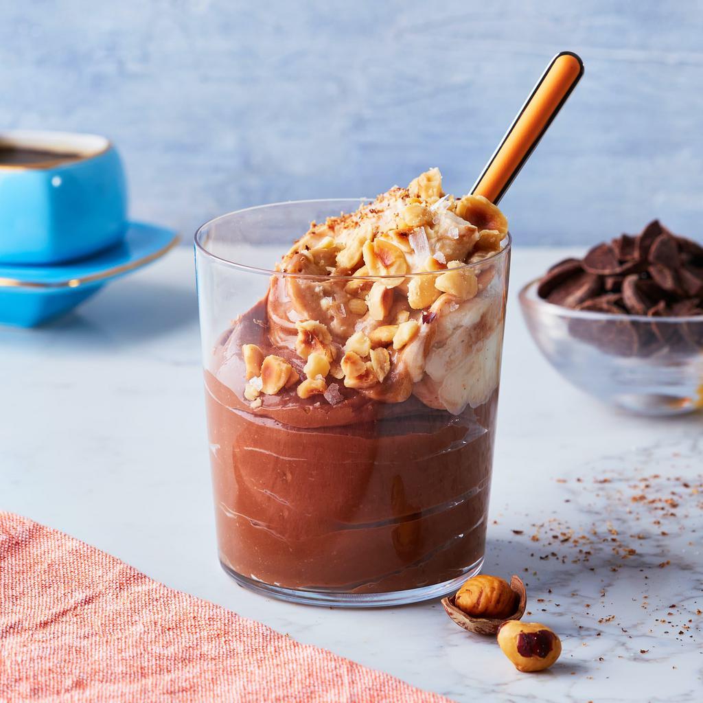 Praline Pud · This decadent hazelnut-praline pudding combines rich chocolate pudding with a layer of hazelnut-praline whipped cream, roasted hazelnut crunch and a whisper of flaky salt and nutmeg | Allergen: Milk, Egg, Tree Nuts