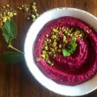 Beets Hummus Mezza · Hummus mixed with roasted beets topped with pistachio and drizzled with olive oil.